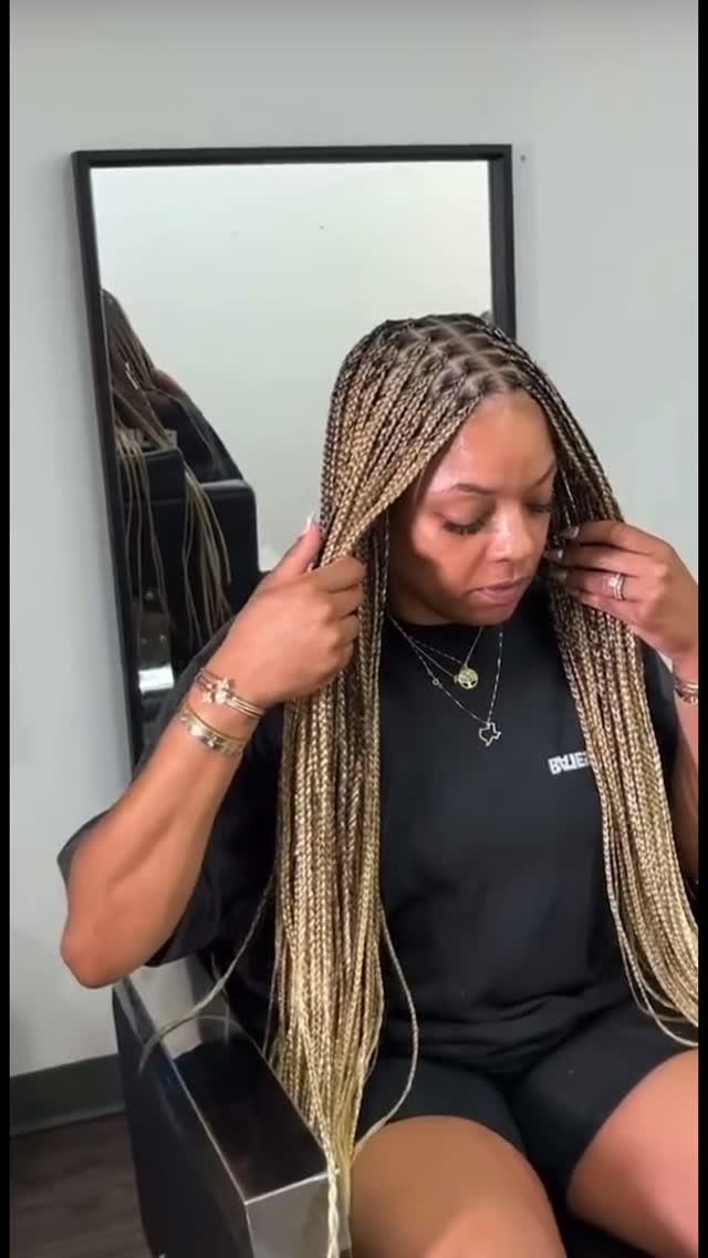 Long honey-blonde knotless braids worn loose, photographed in the salon